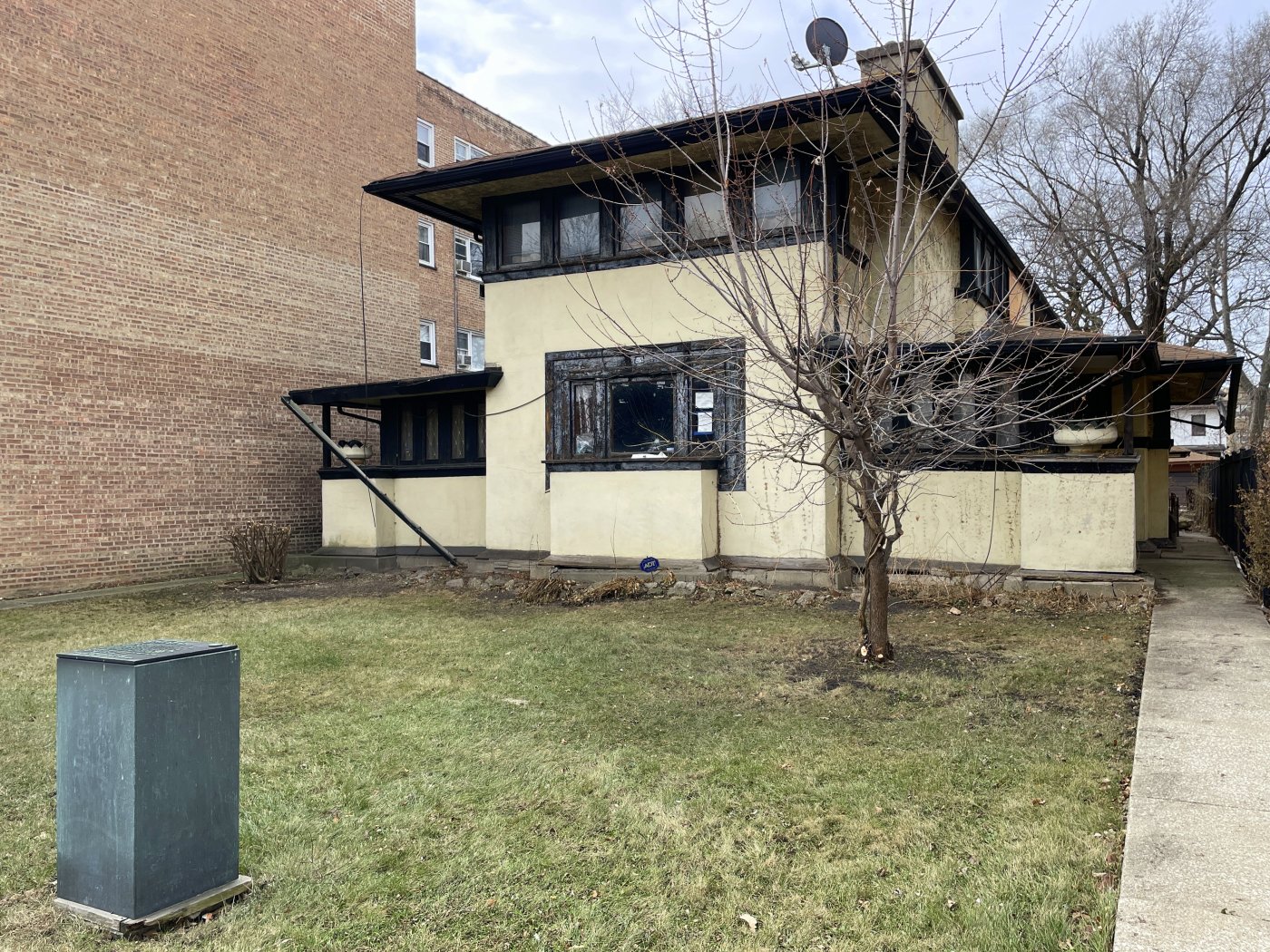 Stucco Prairie-period house by Frank Lloyd Wright with Chicago Landmark plaque in front.