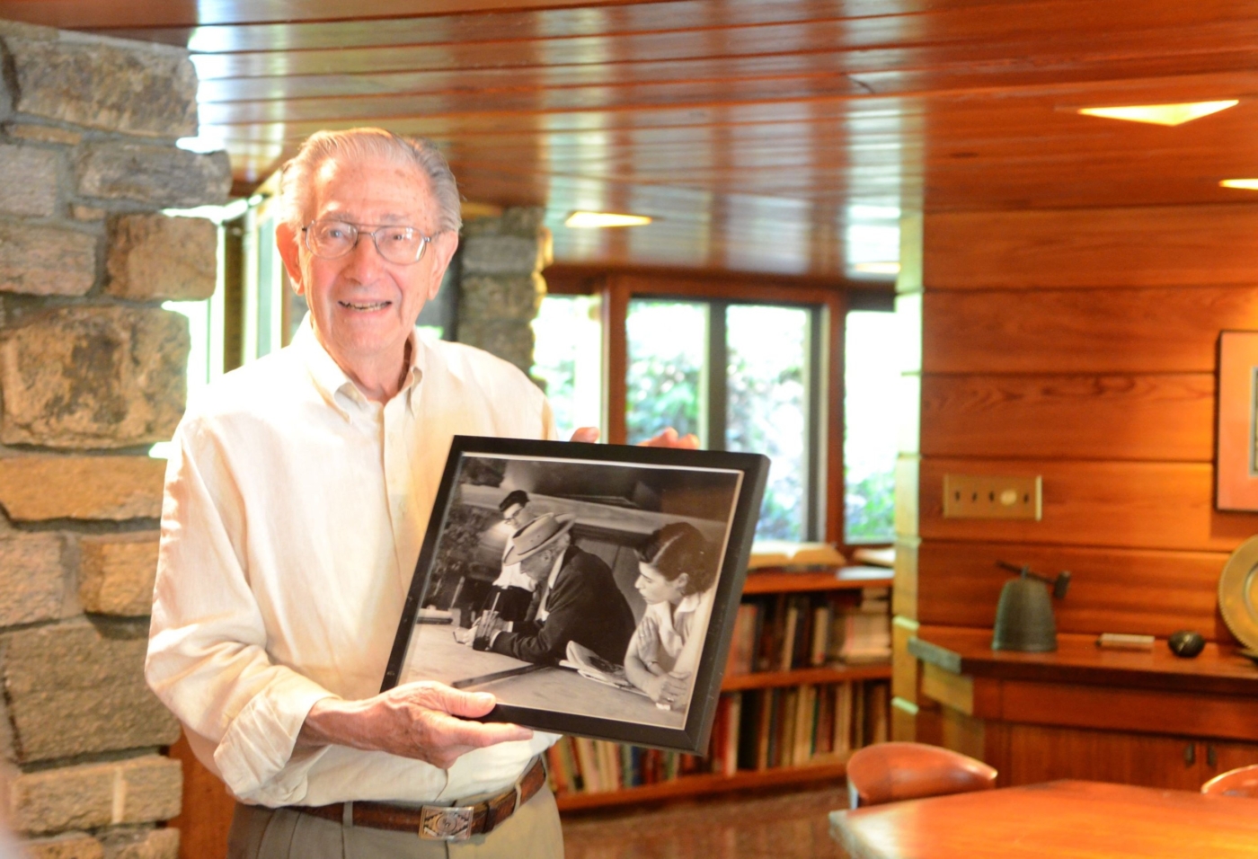 Roland Reisley holding a framed photo of Frank Lloyd Wright at work