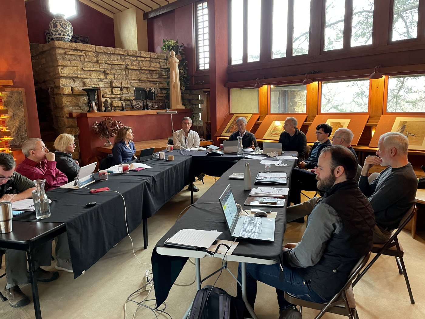 A group of people seated around a table holding a meeting inside at Taliesin